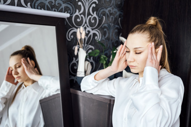 工作中的偏头痛，频繁头痛与工作能力。疲惫不堪的女商人下班后坐在家里的床上头痛。办公室的女职员在工作时感觉不舒服图片下载