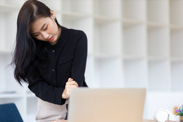 一位年轻的女职员在办公室里做伸展运动，以缓解工作带来的疼痛。图片下载