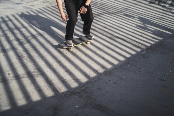 一个人在阳光下的滑板公园玩滑板的特写图片下载