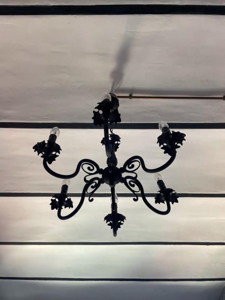 复古古色古香的老暗青铜吊灯，灯泡形状的蜡烛从白色天花板上挂着，周围是复古的墙壁。怀旧照明概念。复古风格的库存照片图片下载