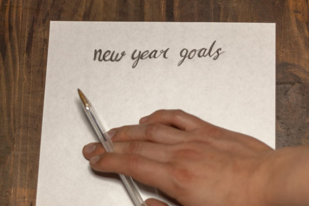 一名男子正在木制背景的一张白纸上制定新年目标图片下载