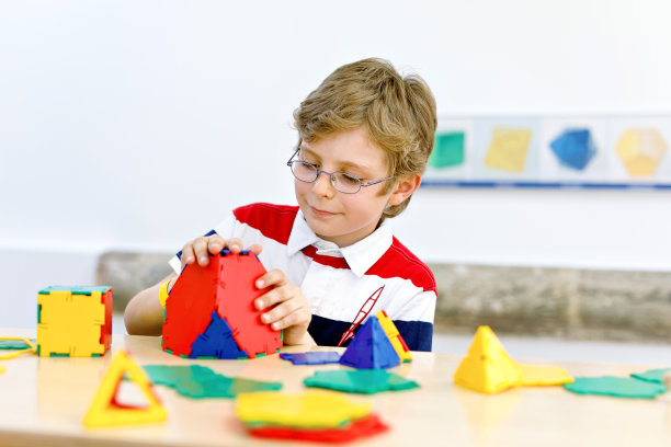 戴着眼镜的快乐小男孩喜欢建造和创造几何图形，学习数学和几何图片下载