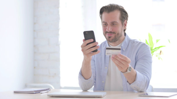 快乐的年轻人在办公室用智能手机网上购物图片下载