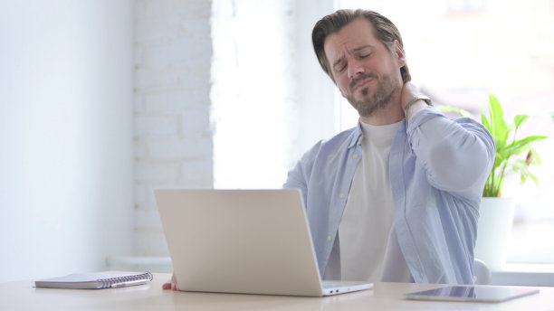 年轻男子使用笔记本电脑时颈部疼痛图片下载