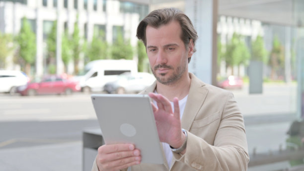 年轻人站在户外使用电子平板电脑图片下载