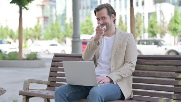 坐在户外长凳上的年轻人指着相机图片下载