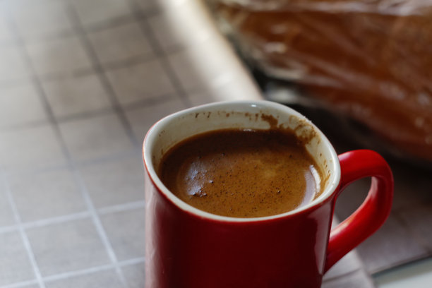 去焦红色的咖啡。早上在咖啡店的旧木桌上，热气腾腾的咖啡冒着烟。有泡沫的红色杯子。焦距模糊图片下载