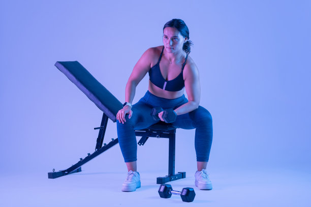 穿着运动服的女人坐在长凳上做肱二头肌练习图片下载
