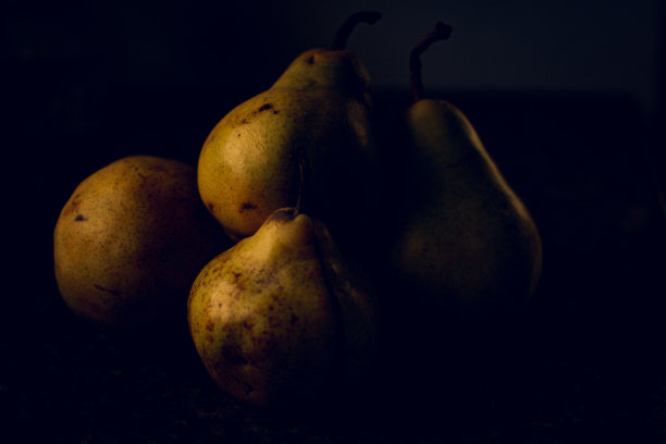 在黑暗中，黄色的梨在表面上的特写图片下载