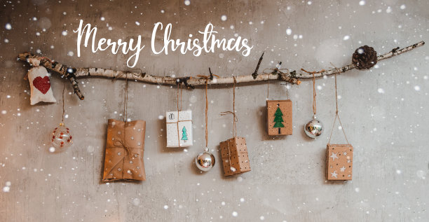 圣诞礼物用牛皮纸包装，手工制作的装饰品挂在一根绳子上，绳子系在一根棍子上，靠在灰色的混凝土墙上。图片下载