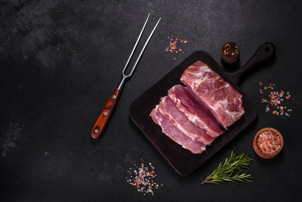 一块新鲜的生猪肉，加香料，盐和香草，放在木砧板上图片下载