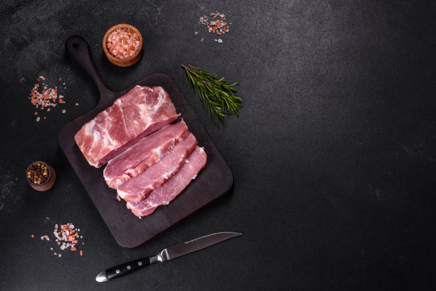 一块新鲜的生猪肉，加香料，盐和香草，放在木砧板上图片下载