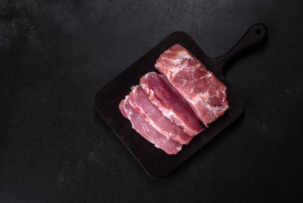 一块新鲜的生猪肉，加香料，盐和香草，放在木砧板上图片下载