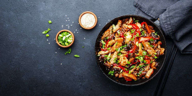 与火鸡肉片，辣椒粉，香菇，香葱和芝麻一起放入煎锅中翻炒。亚洲菜。黑色石材厨房餐桌背景，俯视图图片下载