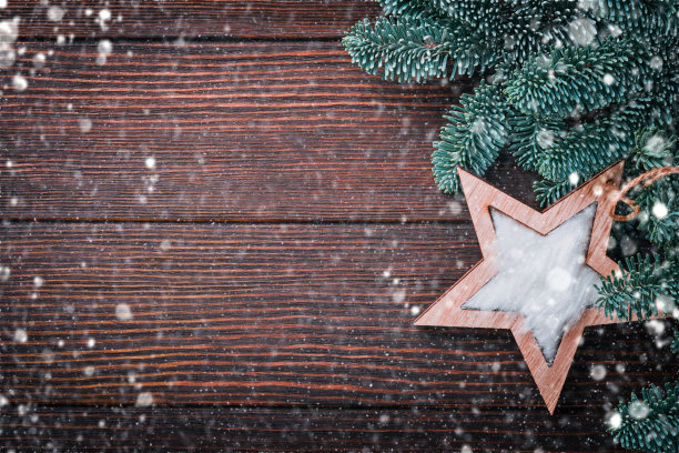 圣诞节或新年背景与杉木树枝和木制雪花和星星圣诞球，礼品盒上的黑色木制背景。放短信的地方。圣诞贺卡。图片下载