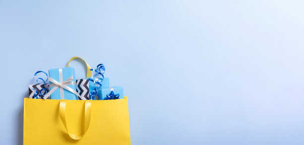 许多圣诞假期礼物的概念。礼品盒与蝴蝶结在一个礼品袋上的蓝色背景平铺，顶视图图片下载