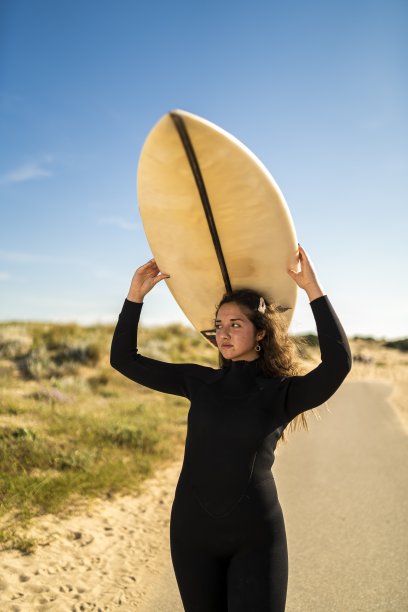 垂直拍摄的一个迷人的女性举着一个冲浪板在她的头上图片下载
