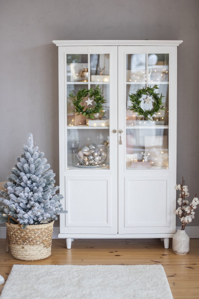斯堪的纳维亚风格的室内装饰，白色的餐具柜上挂着绿色的花环。锅里的圣诞树。图片下载