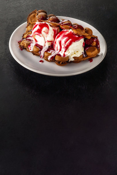 香港巧克力泡泡华夫饼配冰淇淋和草莓或覆盆子糖浆，黑色背景，复制空间。图片下载