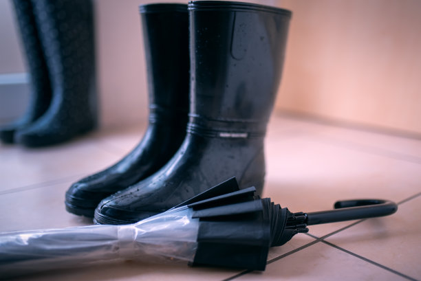 黑色胶靴和一把伞放在走廊的地板上图片下载