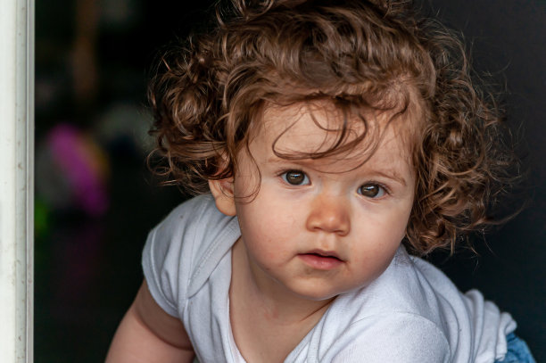 一个可爱的孩子卷发和严肃的面部表情的肖像图片下载