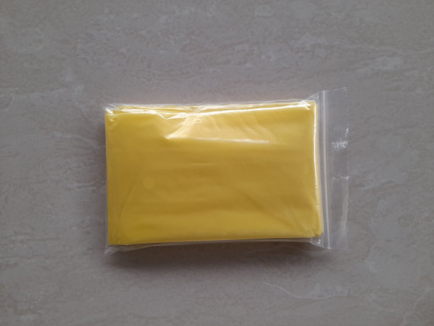 黄色塑料雨衣包装采用塑料与木制桌子背景。图片下载