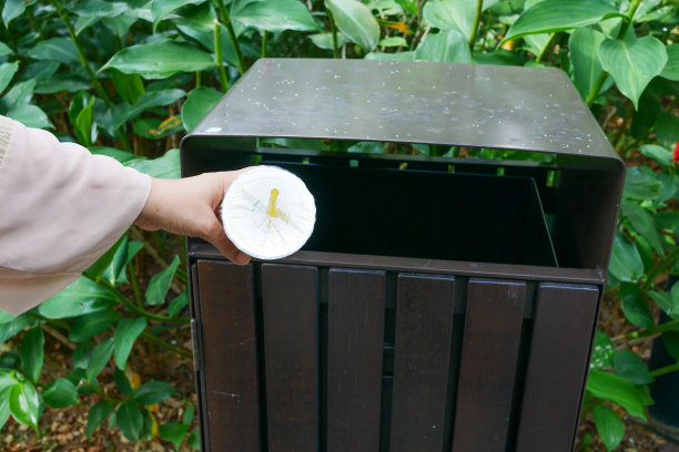 妇女用手把空的塑料水瓶扔进垃圾桶或垃圾箱图片下载