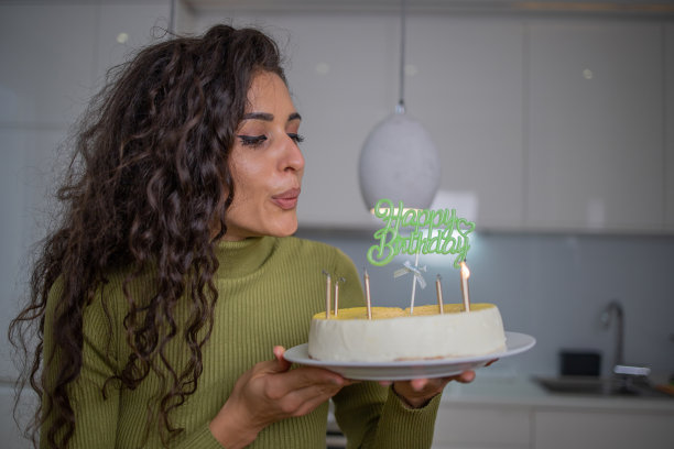 快乐的女士拿着生日蛋糕和蜡烛在家里图片下载
