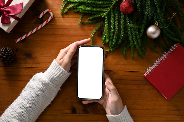 俯视图，一个女性手拿智能手机模型在她的工作空间圣诞主题图片下载