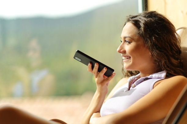 快乐的女人坐在椅子上听写电话留言图片下载