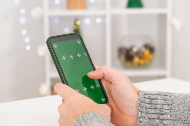 一名男子把手机直立着，屏幕是绿色的。带有chromakey的手机。副本的空间。广告的概念，新年假期，圣诞节。图片下载