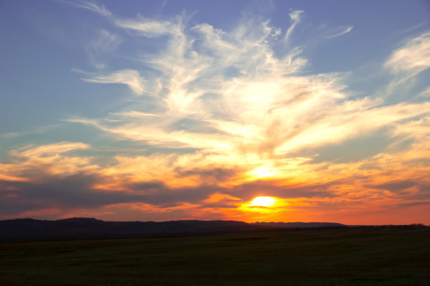 山和田野上的日落，太阳在卷云后面。图片下载