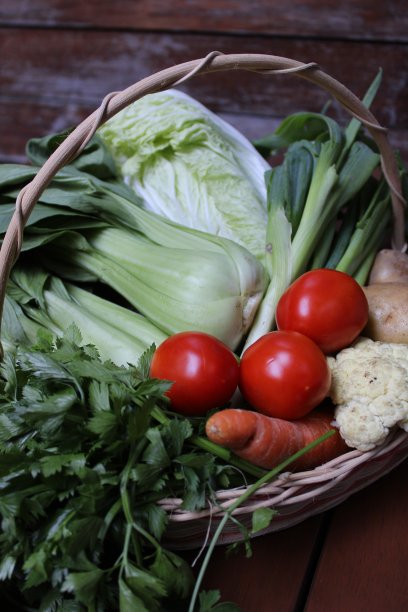 各种新鲜和有机蔬菜在柳条篮子上的木背景图片下载