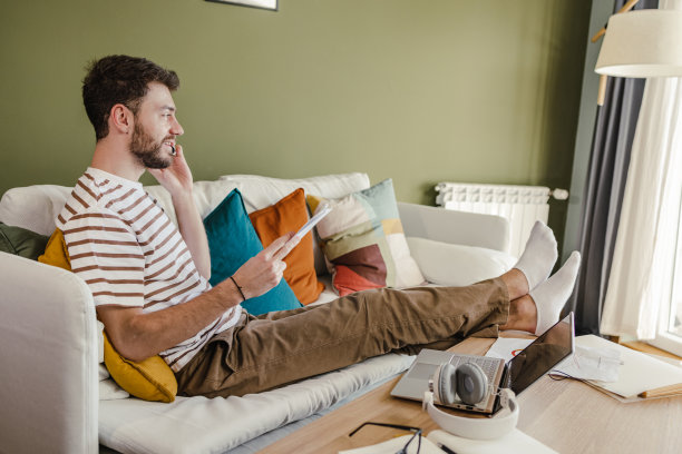 年轻人在家里工作，双腿交叉坐在沙发上图片下载