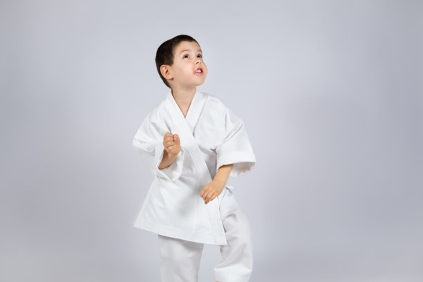 一个穿着和服的小男孩在白色背景上练习空手道。图片下载