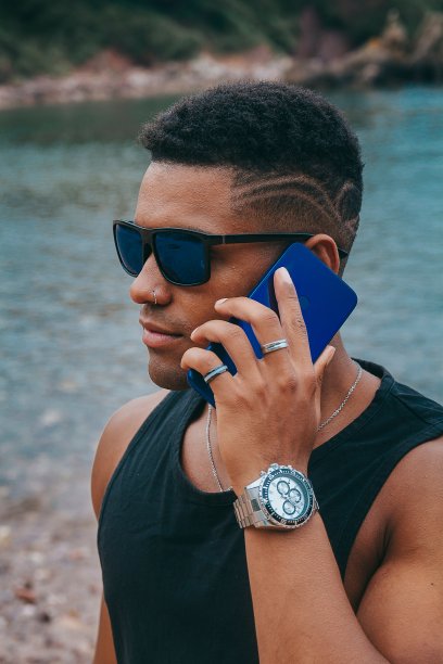 一个戴着墨镜的年轻男子以湖为背景打电话的美丽照片图片下载