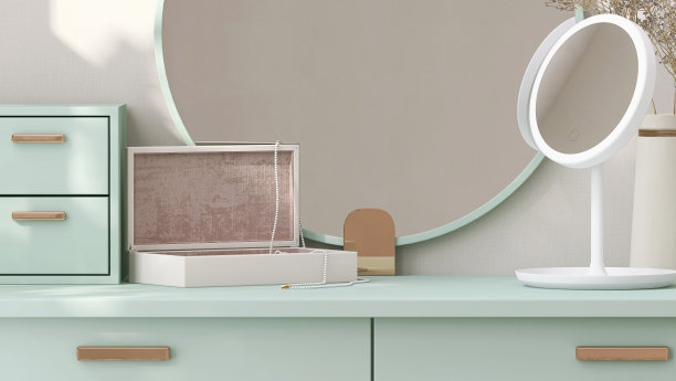 简约和当代的柔和绿色梳妆台与站立的梳妆镜，抽屉和首饰盒在斑驳的阳光从窗户在白墙的卧室图片下载