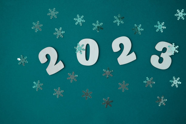 绿色背景上的木制数字和银色雪花。2023年新年。图片下载