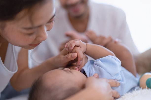 妈妈和爸爸快乐快乐戏弄亚洲婴儿新生儿有乐趣看着父母的脸图片下载