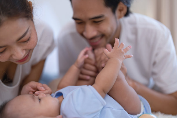 妈妈和爸爸快乐快乐戏弄亚洲婴儿新生儿有乐趣看着父母的脸图片下载