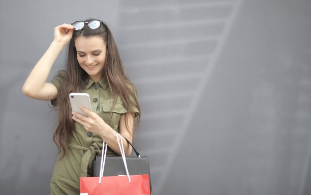 一个戴眼镜的美女在模糊的背景下查看手机的照片图片下载