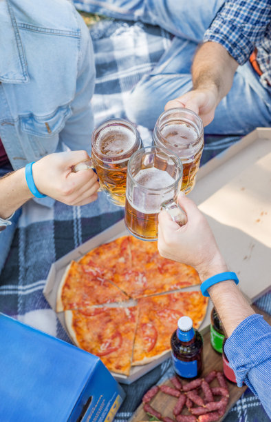 一群朋友在草坪上野餐，一边喝啤酒，一边吃披萨和香肠。顶视图和复制空间图片下载