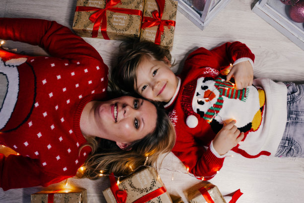 穿着圣诞毛衣的母女俩坐在一大堆礼品盒中间。图片下载