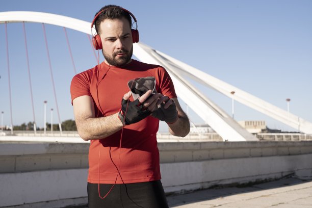 一个戴着红色耳机的男性在街上慢跑时使用手机的特写镜头图片下载