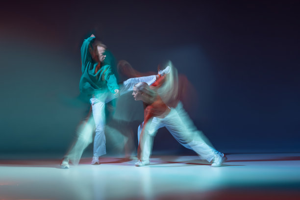 年轻的男人和女人跳舞的肖像在深蓝色的背景上与混合的灯光分离。情绪图片下载