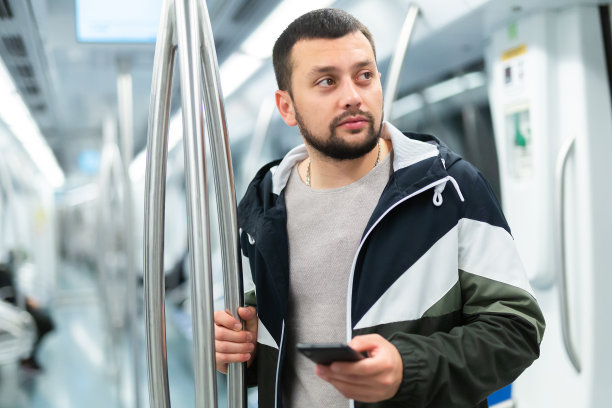 年轻男子在乘坐地铁时使用智能手机图片下载