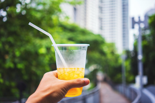 有人举起手，把冰镇的饮料举向公园的天空图片下载