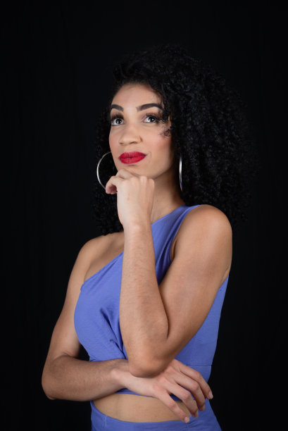 美丽，严肃的年轻女子的肖像。手放在下巴上。穿着蓝色的衣服。图片下载