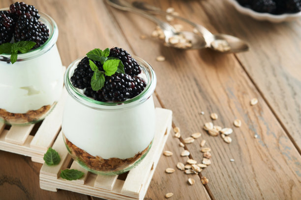 酸奶配格兰诺拉麦片，黑莓浆果水果和什锦麦片，装在木制背景的玻璃罐中。健康早餐的概念。健康的早餐，俯视图图片下载