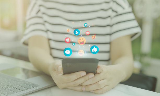 社交媒体的概念。女士使用智能手机，智能手机屏幕上方有“点赞”、“留言”、“微笑爱的表情”和“聊天”等通知图标。图片下载